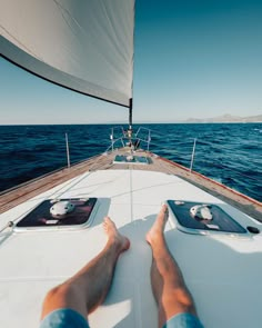 a person laying down on the deck of a sailboat in the open water with their feet propped up