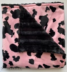 a pink and black cow print blanket on top of a white wall