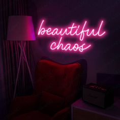 a neon sign that says beautiful chaos on the wall next to a red chair in a dark room