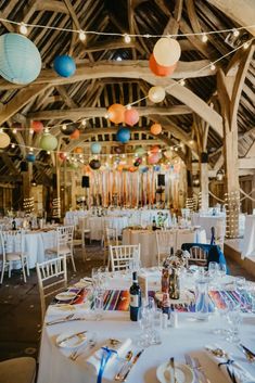 tables and chairs are set up for an event with paper lanterns hanging from the ceiling