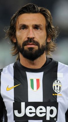 a man with long hair and beard wearing a black and white shirt is looking at the camera