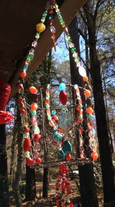 a wind chime hanging from the side of a building in a forest with lots of trees