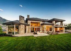 a large house sitting in the middle of a lush green field with mountains in the background