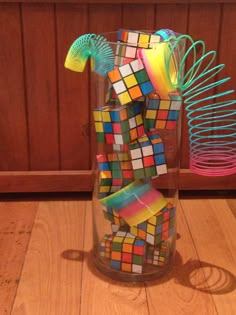 a vase filled with lots of different colored rubiks on top of a wooden floor