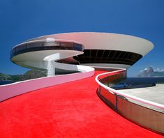 a red carpeted walkway leading up to a building with curved walls and circular windows