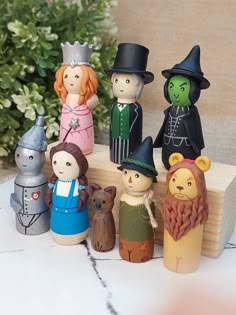 a group of wooden toy figurines sitting on top of a white table next to green plants