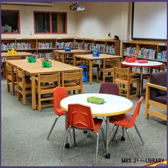 an empty classroom with tables and chairs in the middle is full of children's books