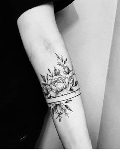 a black and white photo of a woman's arm with a flower tattoo on it