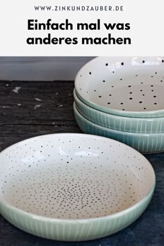 two white and green bowls sitting on top of a wooden table next to each other