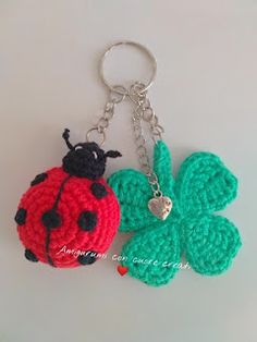 two crocheted ladybug keychains on a white surface one has a clover and the other has a heart