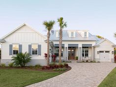 a white house with palm trees in the front yard and driveway leading up to it