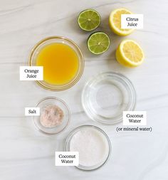 ingredients to make an orange juice recipe laid out on a marble counter top with lemons, coconut water and salt