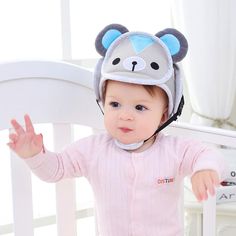 a baby wearing a bear hat while standing in a crib