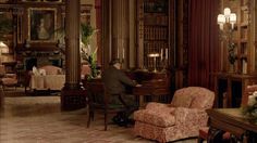 a man sitting at a desk in a room filled with furniture and bookshelves