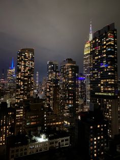 the city skyline is lit up at night with skyscrapers in the foreground and bright lights on the buildings