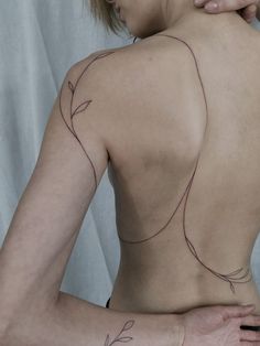 the back of a woman's body with tattoos on her left shoulder and right arm