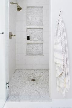 a white bathroom with marble flooring and shelving unit in the shower stall area