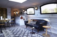 a living room filled with furniture next to a dining room table and window covered in mirrors