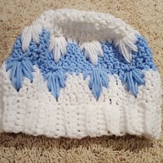 a crocheted blue and white hat laying on the floor next to a rug