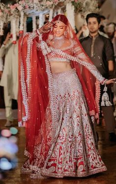 a bride in a red and white lehenga walking down the aisle