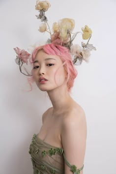 a young woman with pink hair and flowers in her hair is posing for the camera