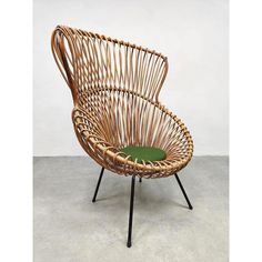 a wicker chair with a green cushion sits on a concrete floor in front of a white wall