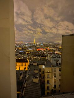 the city is lit up at night with clouds in the sky and buildings on either side