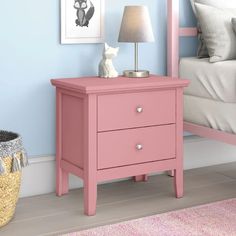 a pink night stand with two drawers and a lamp next to it on a carpeted floor