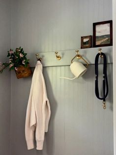 a coat rack with two coats hanging from it's hooks next to a potted plant