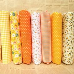 six different colored paper rolls lined up in a row on a brown background with white polka dots and yellow flowers