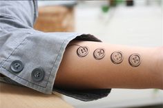 a person's arm with buttons on it that have smiley faces drawn on them