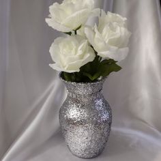 a silver vase with white flowers in it