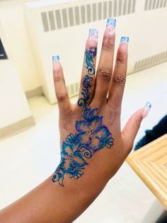 a woman's hand with blue and white designs on it, holding up her left hand