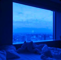 a bed in front of a window with a view of the city