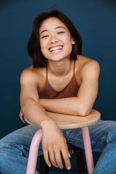 a woman sitting on top of a stool smiling