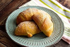 two croissants on a plate with powdered sugar