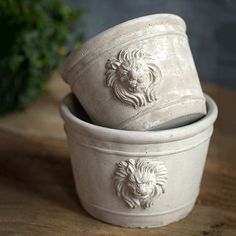 two white ceramic pots sitting on top of a wooden table