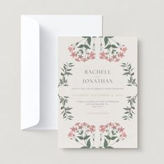 a wedding card with pink flowers and greenery on the front, in white envelope