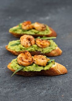 three pieces of bread with shrimp and guacamole on them