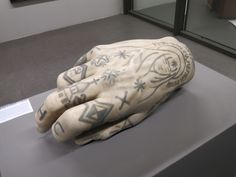 a sculpture of a hand with tattoos on it's palm is displayed in a museum