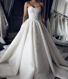 a woman standing in front of a mirror wearing a wedding dress