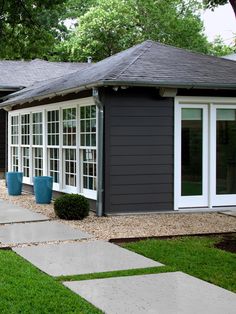 a gray house with two blue planters in the front yard and one on the other side