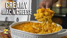 a person scooping macaroni and cheese out of a casserole dish