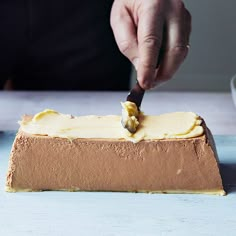 a person is spreading icing on a cake with a knife and fork in it