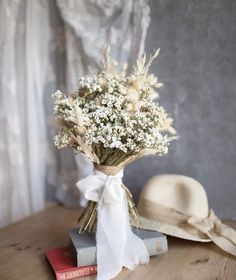 a bouquet of baby's breath sitting on top of a table next to a hat