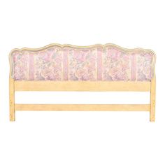 a wooden bed frame with pink and white floral print upholstered on the headboard