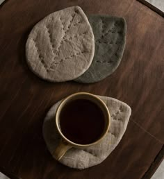 a cup of coffee sitting on top of a wooden table next to an oven mitt