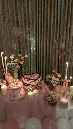 a table topped with a heart shaped cake surrounded by balloons