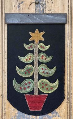 an embroidered christmas tree hanging on the side of a wooden door