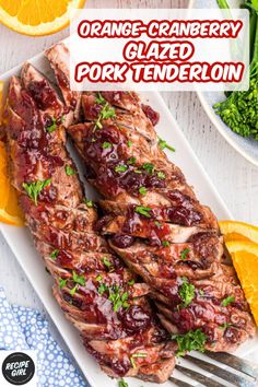 orange cranberry glazed pork tenderies on a white platter with garnish